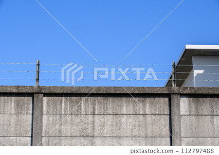 concrete wall with barbed wire 112797488