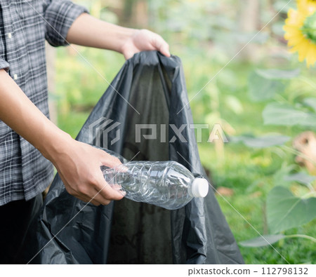 Man's hands pick up plastic bottles, put garbage in black garbage bags to clean up at parks, avoid pollution, be friendly to the environment and ecosystem 112798132