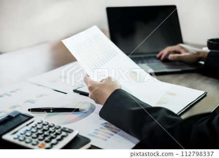 The businessman hand sits at their desks and calculate financial graphs showing results about their investments, planning a successful business growth process The businessman hand sits at their desks and calculate financial graphs showing results about their investments, planning a successful business growth process 112798337