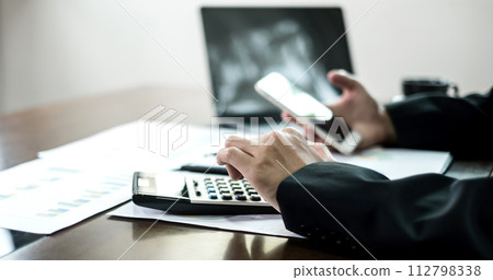 The businessman hand sits at their desks and calculate financial graphs showing results about their investments, planning a successful business growth process 112798338