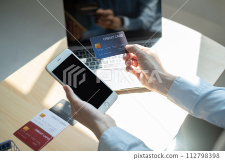 Asian girl shopping online holding credit and using smartphone enter their card number in the mobile phone app to purchase and payment in internet store 112798398