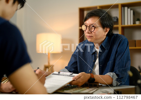 Male customer putting signature on agreement with contractor at office Male customer putting signature on agreement with contractor at office 112798467
