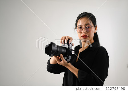 Beautiful female photographer with a dslr camera working at her studio 112798498