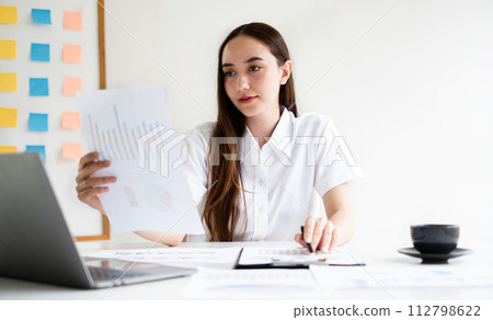 Asian businesswoman sit at their desks and calculate financial graphs showing results about their investments, planning a successful business growth process 112798622