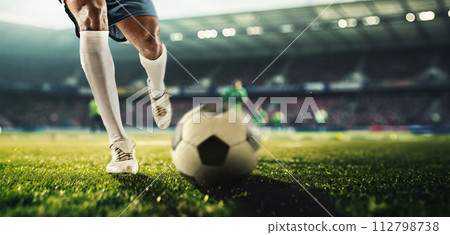 Male legs, football player in motion on filed dribbling ball, playing soccer at 3D stadium model with blurred tribune on background. 112798738