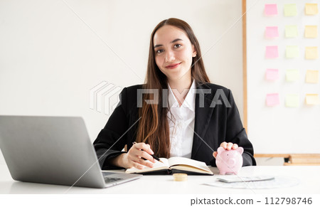 Asian woman putting coin into piggy bank. Saving money with coins Step into a business that is growing to be successful and save for retirement concepts Asian woman putting coin into piggy bank. Saving money with coins Step into a business that is growing to be successful and save for retirement concepts 112798746