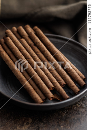 Chocolate Wafer Rolls on plate on dark table. Chocolate Wafer Rolls on plate on dark table. 112798776