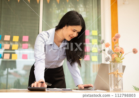 Asian businesswoman sit at their desks and calculate financial graphs showing results about their investments, planning a successful business growth process Asian businesswoman sit at their desks and calculate financial graphs showing results about their investments, planning a successful business growth process 112798803