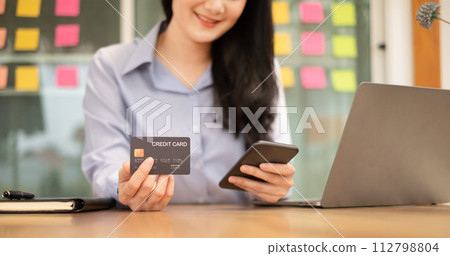 Asian girl shopping online holding credit and using smartphone enter their card number in the mobile phone app to purchase and payment in Internet store Asian girl shopping online holding credit and using smartphone enter their card number in the mobile phone app to purchase and payment in Internet store 112798804