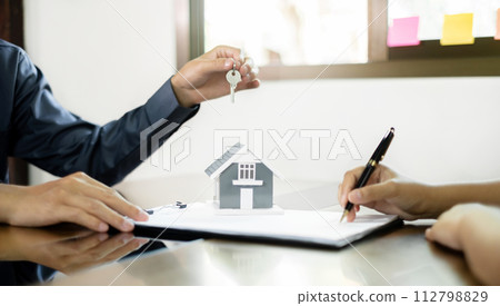Real estate agent broker hand over the house key to the new owner after completing the signing according to agreement renting a house and buy house insurance officially completed Real estate agent broker hand over the house key to the new owner after completing the signing according to agreement renting a house and buy house insurance officially completed 112798829