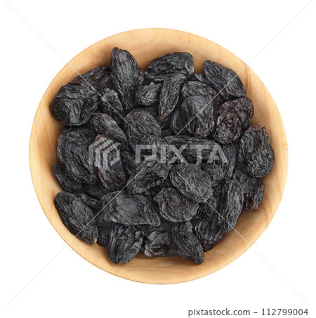 Black raisin iin wooden bowl solated on white background . Top view. Flat lay 112799004