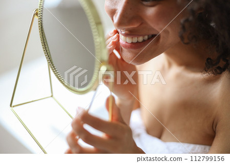 She smiles at her reflection in the mirror, showcasing her happy gesture 112799156