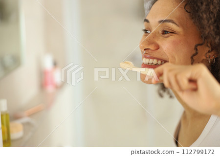a woman is brushing her teeth in front of a mirror in a bathroom 112799172