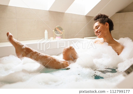 A woman smiling, bathing in a foamfilled bathtub, having fun A woman smiling, bathing in a foamfilled bathtub, having fun 112799177