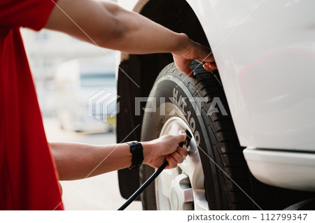 A man is inflating a tire with a tire inflator A man is inflating a tire with a tire inflator 112799347