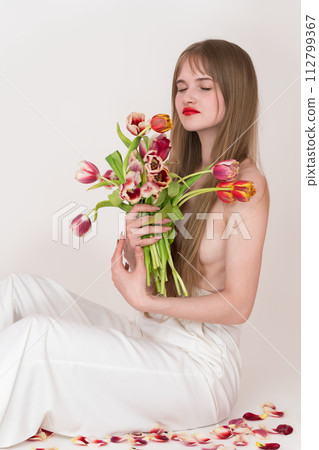Half naked woman with closed eyes holding bouquet of tulips for Woman's Day, using them to cover her chest. Her serene expression and flowing blonde hair add to overall beauty of image Half naked woman with closed eyes holding bouquet of tulips for Woman's Day, using them to cover her chest. Her serene expression and flowing blonde hair add to overall beauty of image 112799367