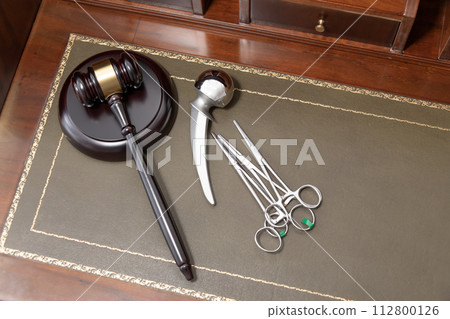 A professional judge's gavel lies next to medical tools, symbolizing legal issues in healthcare. 112800126