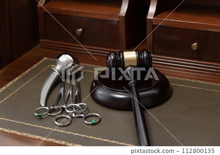 A professional judge's gavel lies next to medical tools, symbolizing legal issues in healthcare. 112800135