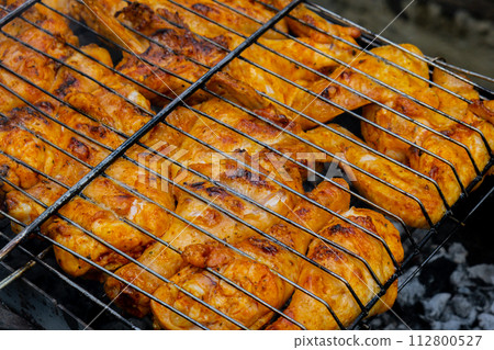 BBQ picnic time Roasted chicken legs and wings on grill. Grilling meat on outdoor grill grid tasty barbeque chicken steak with smoke flames juicy meat in the backyard 112800527