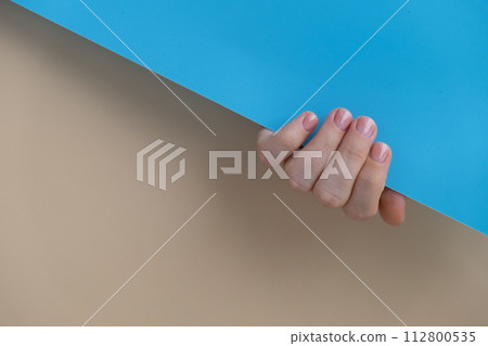 Pastel softness manicured nails on beige blue background. Woman showing her new manicure in colors of pastel palette. Simplicity decor fresh spring vibes earth-colored neutral tones 112800535