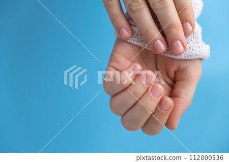 Pastel softness manicured nails on blue background. Woman showing her new manicure in colors of pastel palette. Simplicity decor fresh spring vibes earth-colored neutral tones 112800536