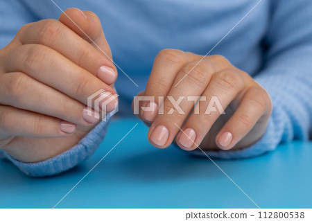 Pastel softness manicured nails on blue background. Woman showing her new manicure in colors of pastel palette. Simplicity decor fresh spring vibes earth-colored neutral tones Pastel softness manicured nails on blue background. Woman showing her new manicure in colors of pastel palette. Simplicity decor fresh spring vibes earth-colored neutral tones 112800538