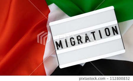 Message MIGRATION on background of UAE flag made from silk. United Arab Emirates national flag with concept of tourism and traveling. Dubai welcoming card Message MIGRATION on background of UAE flag made from silk. United Arab Emirates national flag with concept of tourism and traveling. Dubai welcoming card 112800832