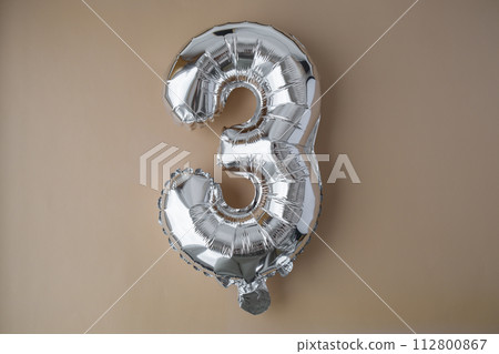 3 three metallic balloon on beige neutral background. Greeting card silver foil balloon number Happy birthday holiday concept. Copy space for text. Celebration party congratulation 3 three metallic balloon on beige neutral background. Greeting card silver foil balloon number Happy birthday holiday concept. Copy space for text. Celebration party congratulation 112800867