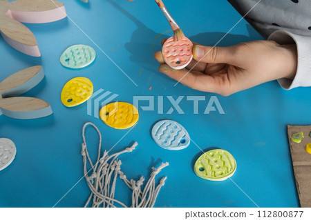 Master class of coloring Unrecognizable artist do it yourself air dry clay crafts for Easter holiday. Decoration gift idea Handmade children craft. Step by step instruction of painting, pressing 112800877