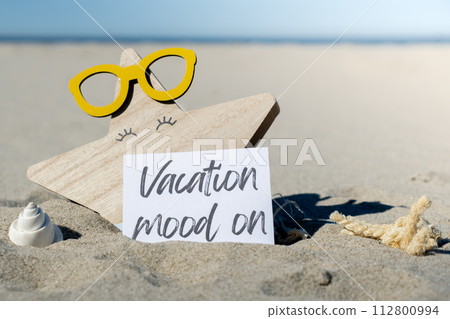 VACATION MOOD ON text on paper greeting card on background of beach chair lounge starfish summer vacation decor. Sandy beach sun. Holiday concept postcard. Travel VACATION MOOD ON text on paper greeting card on background of beach chair lounge starfish summer vacation decor. Sandy beach sun. Holiday concept postcard. Travel 112800994