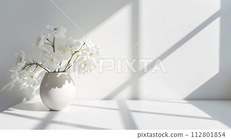 A sophisticated arrangement of fresh flowers in a minimalist vase casts soft shadows on the pristine white surface A sophisticated arrangement of fresh flowers in a minimalist vase casts soft shadows on the pristine white surface 112801854