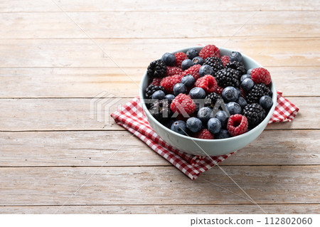 Fresh assortment berries in bowl on wooden table 112802060