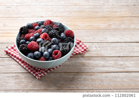 Fresh assortment berries in bowl on wooden table 112802061