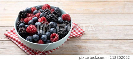 Fresh assortment berries in bowl on wooden table 112802062