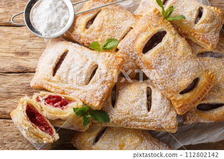 Sweet berry puff pastry with powdered sugar and mint close-up. Horizontal top view Sweet berry puff pastry with powdered sugar and mint close-up. Horizontal top view 112802142