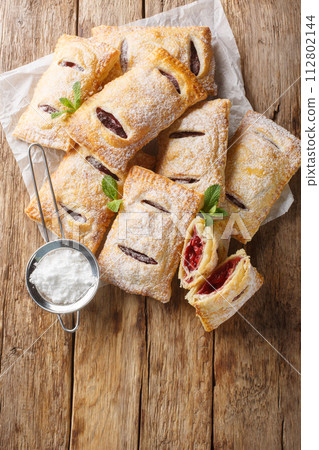 Puff pastry filled with cherry jam close-up. Vertical top view Puff pastry filled with cherry jam close-up. Vertical top view 112802144