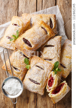 Cherry puff pastry with powdered sugar and mint close-up. Vertical top view 112802145