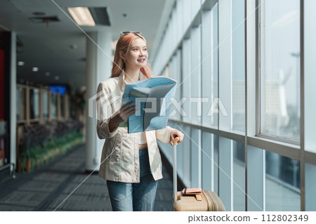 Happy young woman asian is stand in airport near suitcase and reading map 112802349