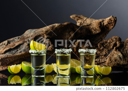 Gold tequila with sea salt and lime slices on a background of old snag. 112802675