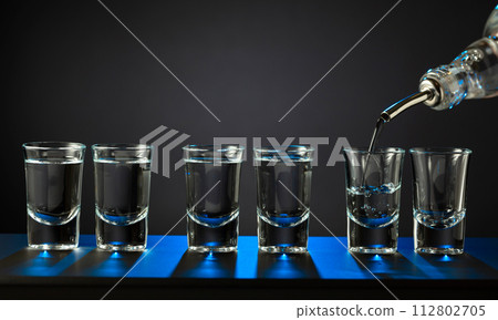 Barman pouring hard spirit into glasses. 112802705