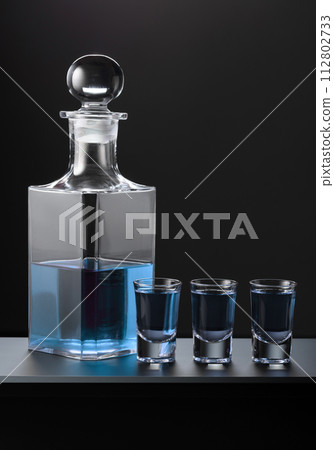 Old decanter and glasses with blue gin. Old decanter and glasses with blue gin. 112802733