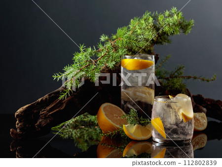 Cocktail gin-tonic with ice and lemon on a black reflective background. 112802839