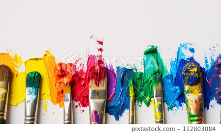An arrangement of colorful paintbrushes dipped in various hues of paint on a pristine white surface An arrangement of colorful paintbrushes dipped in various hues of paint on a pristine white surface 112803084