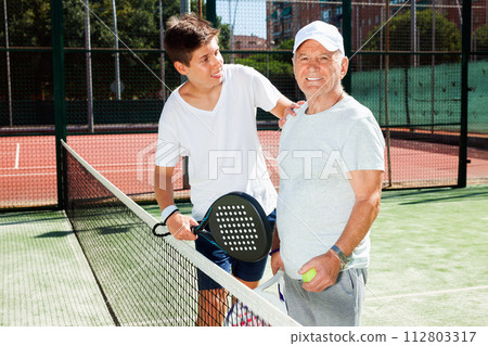 Padel players of different generations talking on court playing paddle Padel players of different generations talking on court playing paddle 112803317