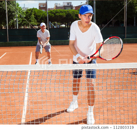 Grandfather and grandson playing tennis court 112803319