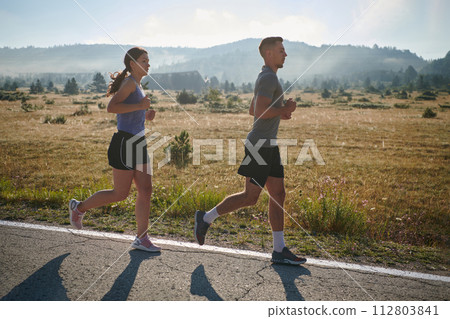 Energized by the beauty of nature, a couple powers through their morning run, their bodies and spirits invigorated. Energized by the beauty of nature, a couple powers through their morning run, their bodies and spirits invigorated. 112803841
