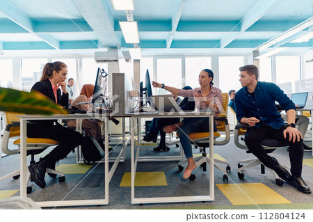Collaborative process of multicultural skilled young business team during brainstorming meeting in office.Diverse group of young people dressed in formal wear cooperating on developing design project 112804124