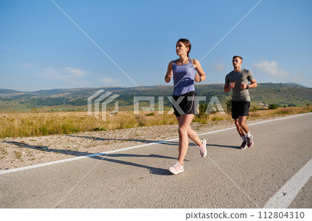 Energized by the beauty of nature, a couple powers through their morning run, their bodies and spirits invigorated. 112804310