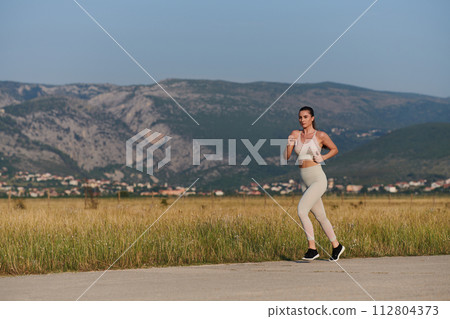 A determined woman athlete trains for success in the morning sun. 112804373
