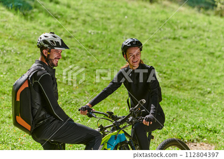 A sweet couple, equipped with bicycles and engrossed in coordinating their journey, checks their GPS mobile and watches while planning scenic routes in the park, seamlessly blending technology and A sweet couple, equipped with bicycles and engrossed in coordinating their journey, checks their GPS mobile and watches while planning scenic routes in the park, seamlessly blending technology and 112804397